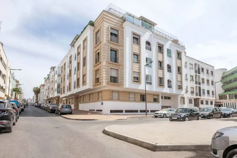 Résidence Tayssir: a cream six-storey corner building with stone trims, cars parked along the street