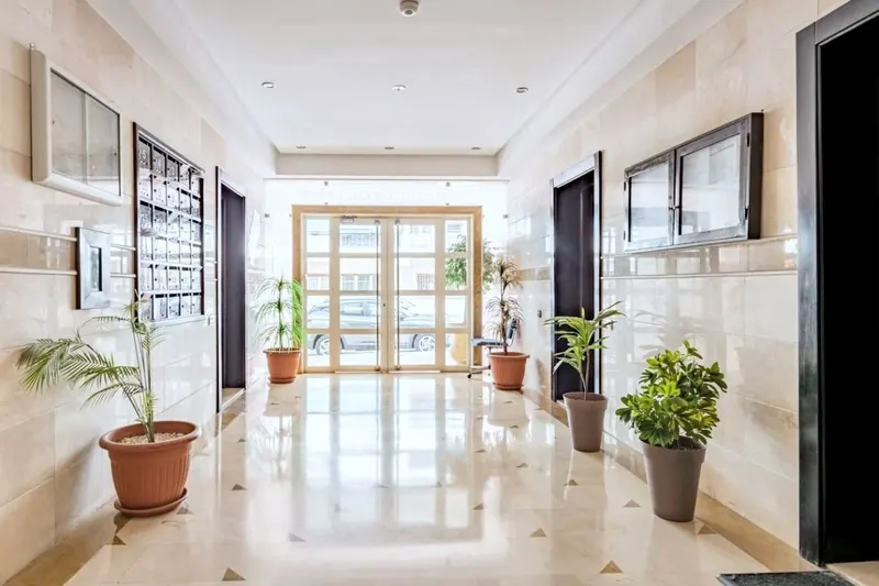 Building hallway with a white marble floor and potted plants