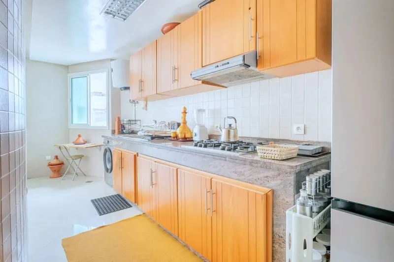 Kitchen with honey-oak cabinets, a gas hob and hood, and the washing machine under the counter