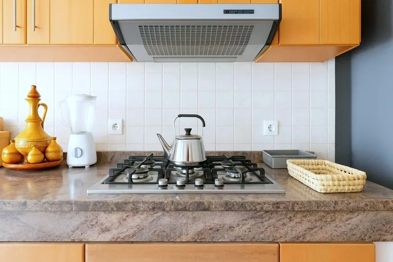 Gas hob with a kettle, a brass teapot set, a blender and a bread basket