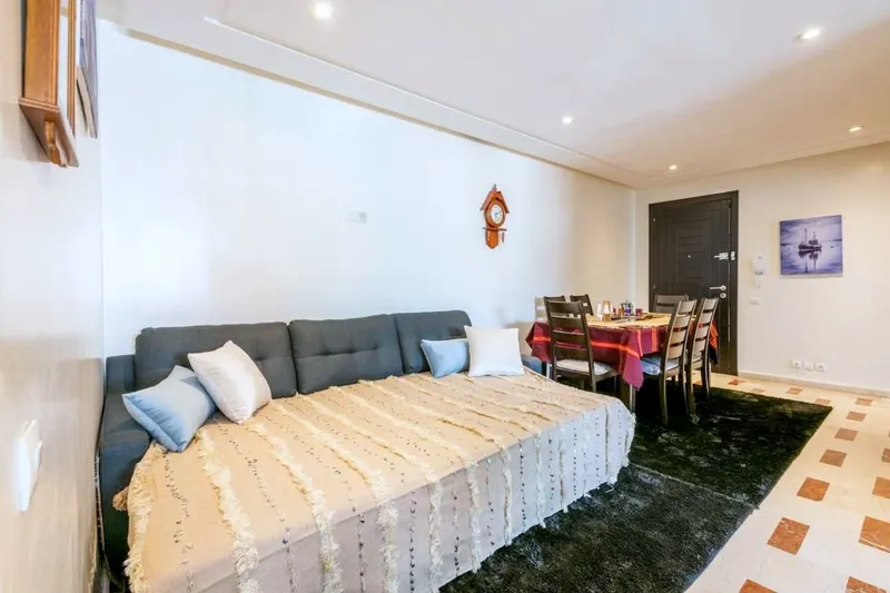 Salon 2 with a sofa bed made up under a cream woven throw, the dining table behind