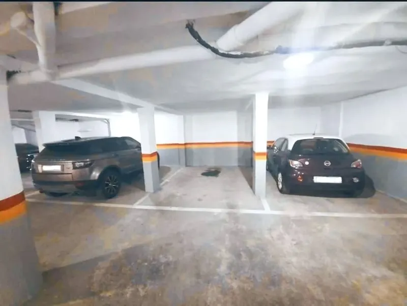 The underground garage with two cars parked between orange-banded pillars